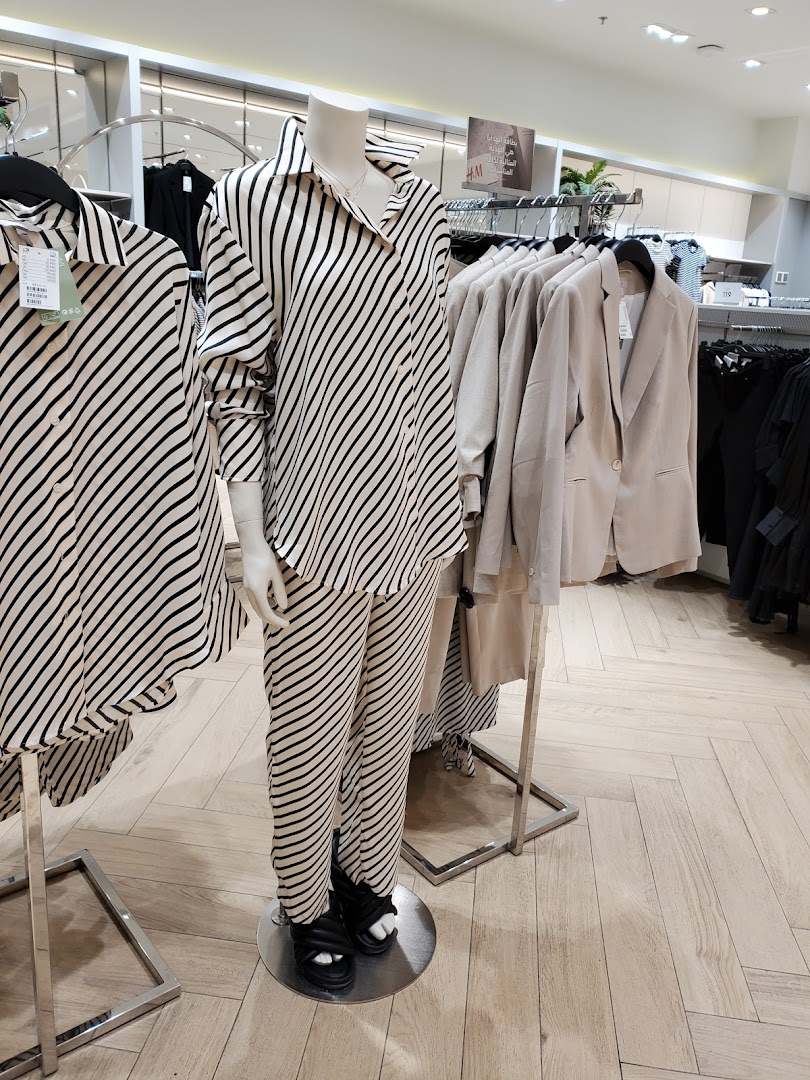 Mannequins display striped and neutral-toned clothing in a retail store.