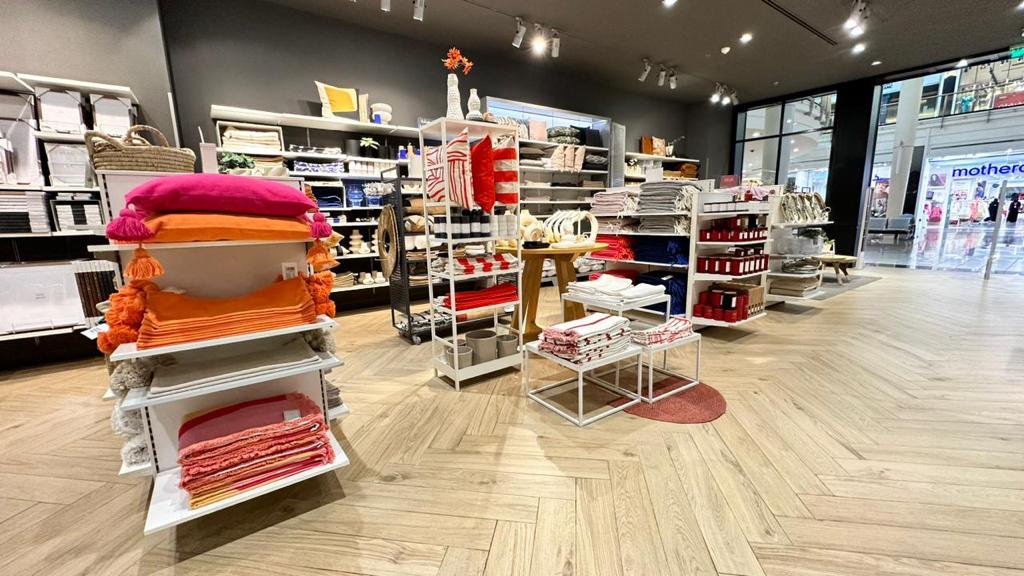 Interior view of an H&M home store showcasing colorful pillows, blankets, and home decor items.