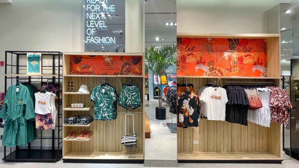 H&M store interior showcasing summer collection with tropical prints and casual wear.