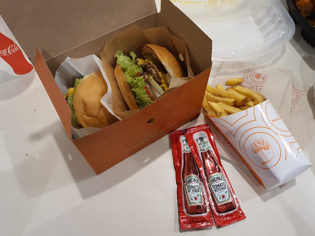 Two delicious burgers and a side of fries from Hamburgini, served with ketchup packets.