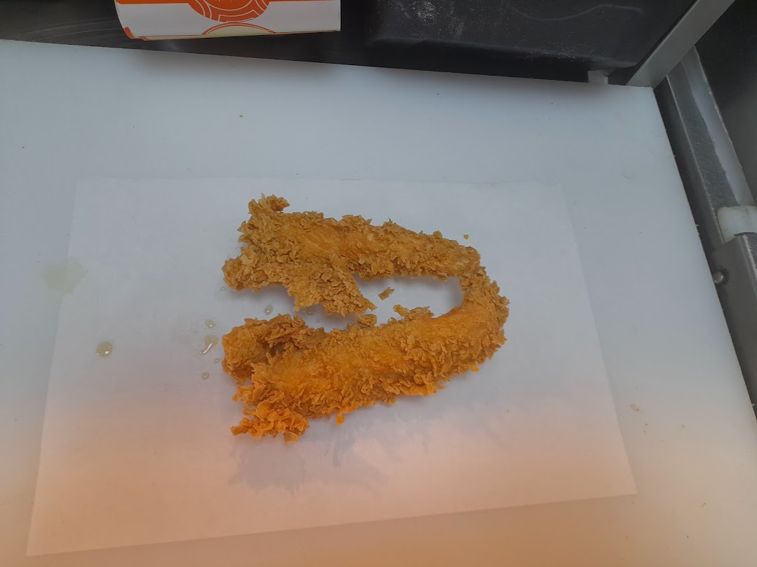 Crispy fried chicken tenders and onion rings on white paper.