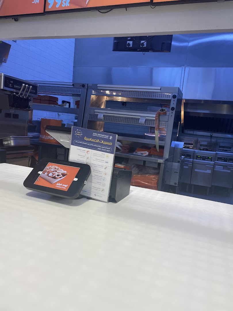 A digital menu tablet displays loaded fries next to an allergen information sign.