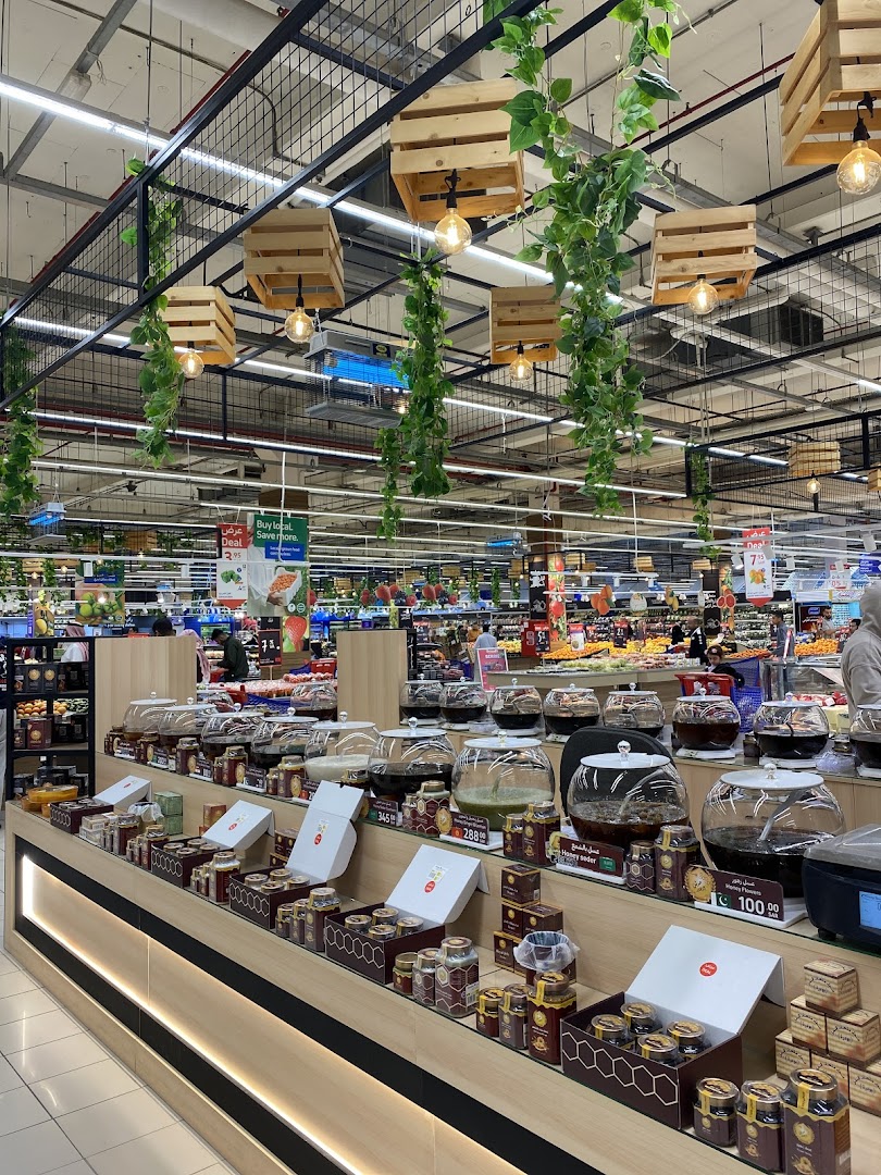 A display of honey products in jars and boxes, with decorative plants and lights hanging from the ceiling.