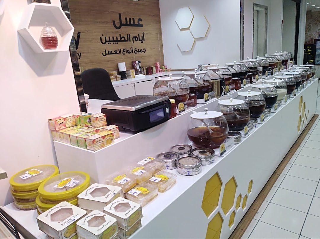 A shop display featuring various types of honey in large glass jars and packaged boxes.