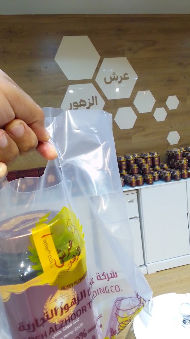 A hand holds a plastic bag with a jar of honey from Honey Alzhoor shop.