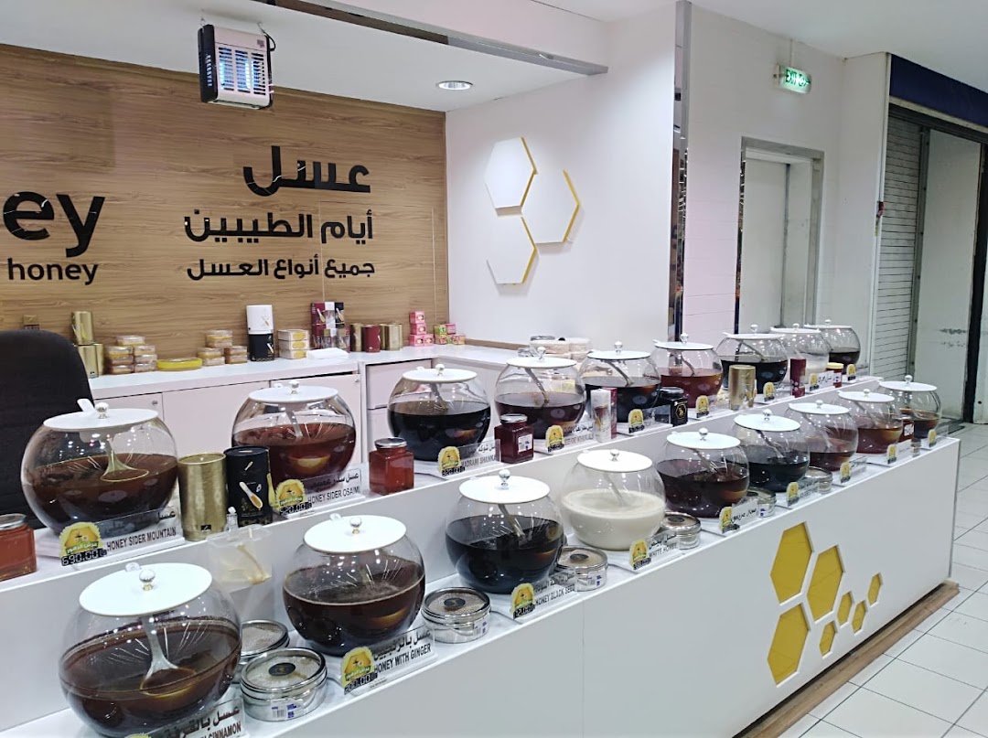 A shop display featuring various types of honey in large glass jars and smaller containers.