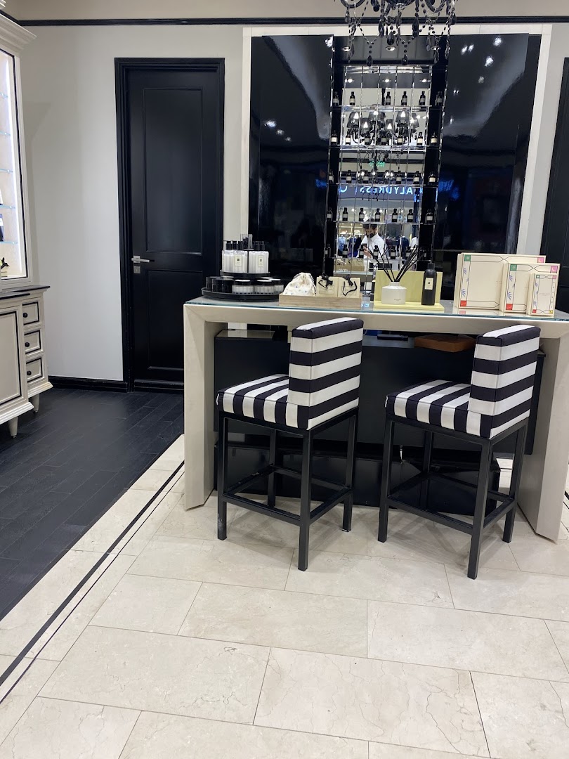Interior shot of a Jo Malone shop with striped bar stools and perfume bottles on display.