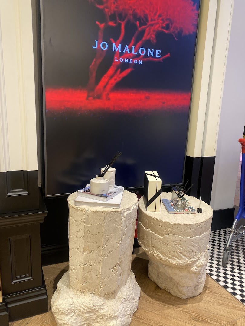 Jo Malone London display featuring diffusers and gift boxes on stone pedestals.