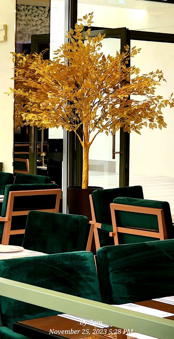 Interior of a cafe with plush green seating and a decorative golden tree.