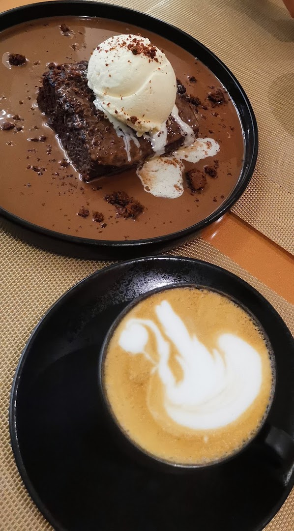 A decadent chocolate brownie with ice cream and a latte with latte art.