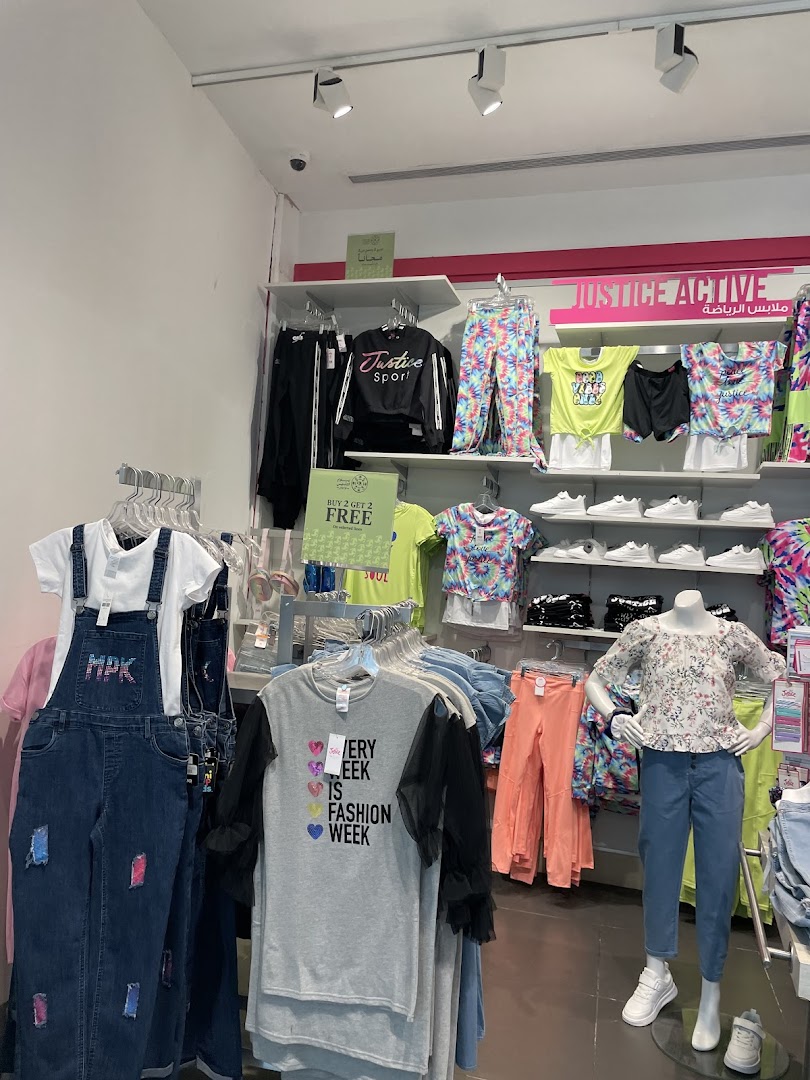 A display of trendy girls' clothing, including activewear, t-shirts, and denim overalls.