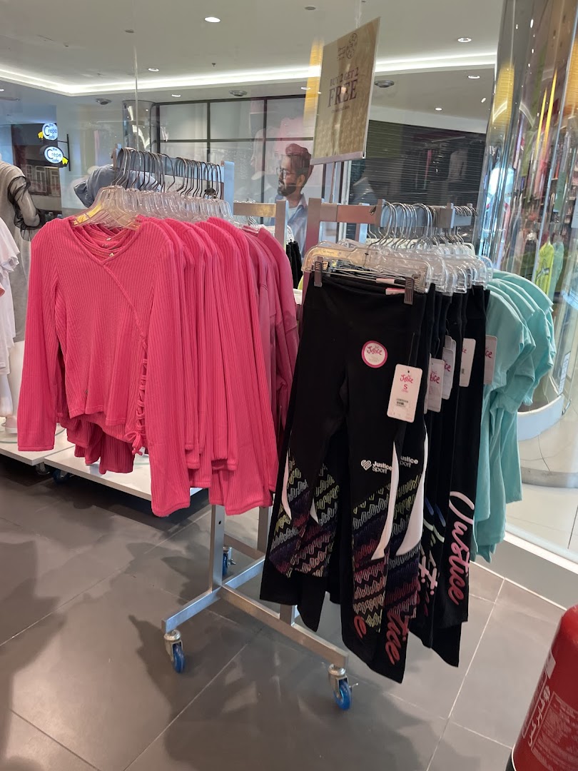 Racks of colorful girls' clothing, including pink tops and patterned leggings, displayed in a store.