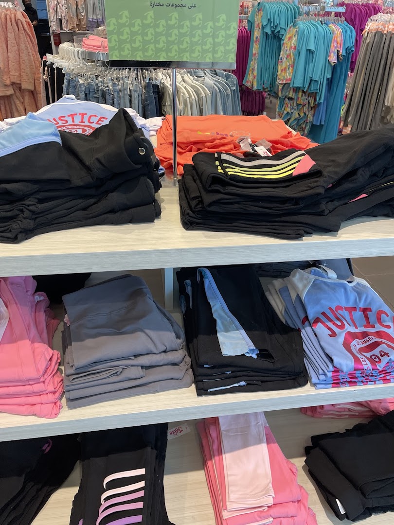 Shelves stocked with colorful apparel, including t-shirts, hoodies, and leggings, from the Justice store.