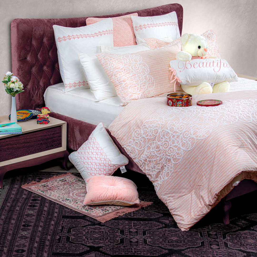 A beautifully made bed with plush bedding, decorative pillows, and a teddy bear.