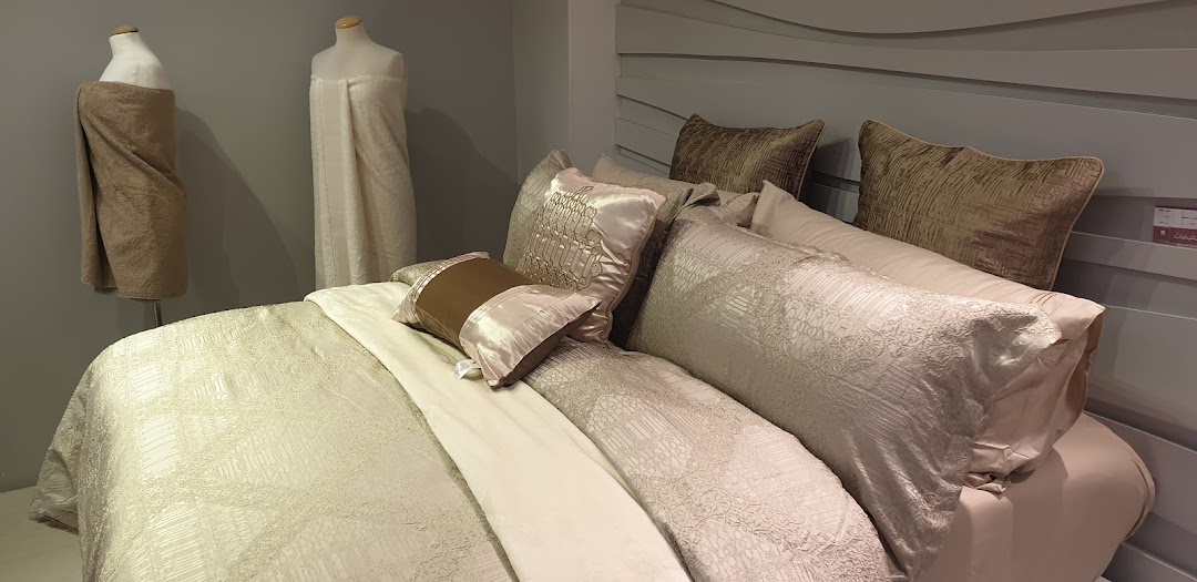 A beautifully made bed with luxurious linens and decorative pillows, alongside mannequins displaying towels.