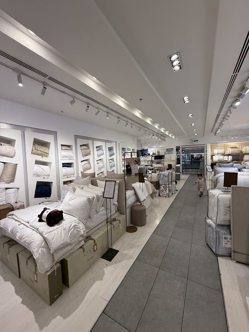 Interior view of Karaz Linen shop showcasing bedding displays and a child walking.