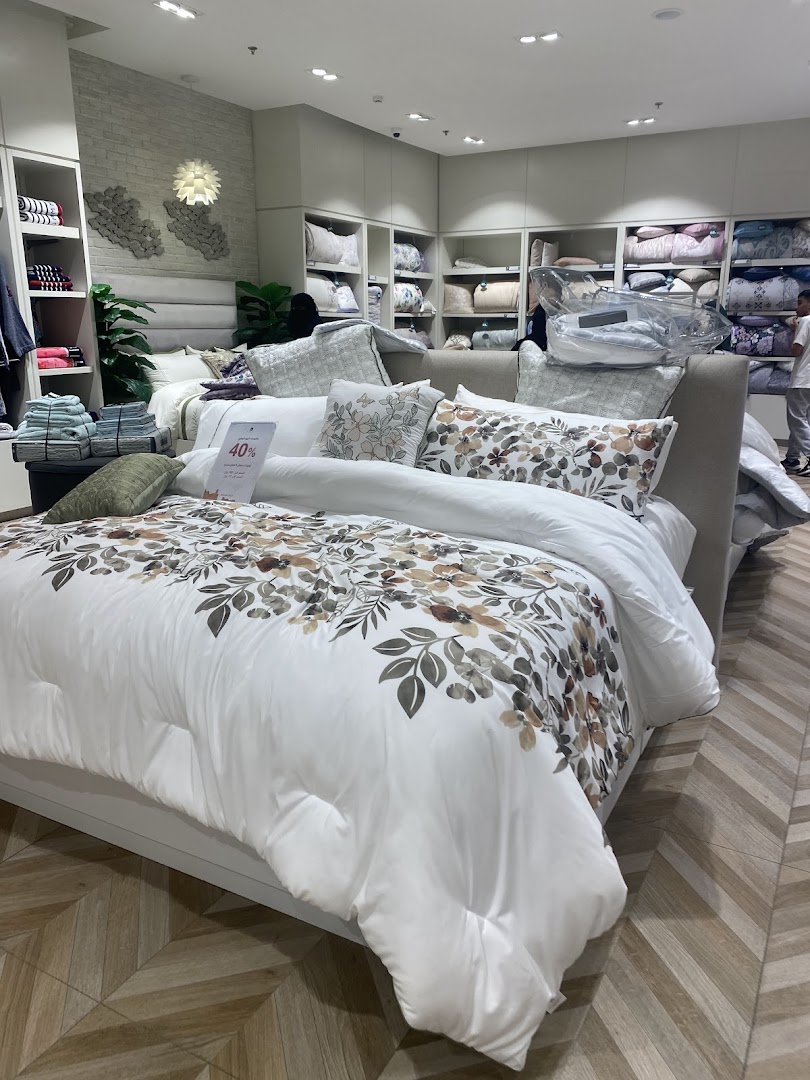 Interior view of Karaz Linen shop showcasing beautifully made beds with floral bedding and pillows.