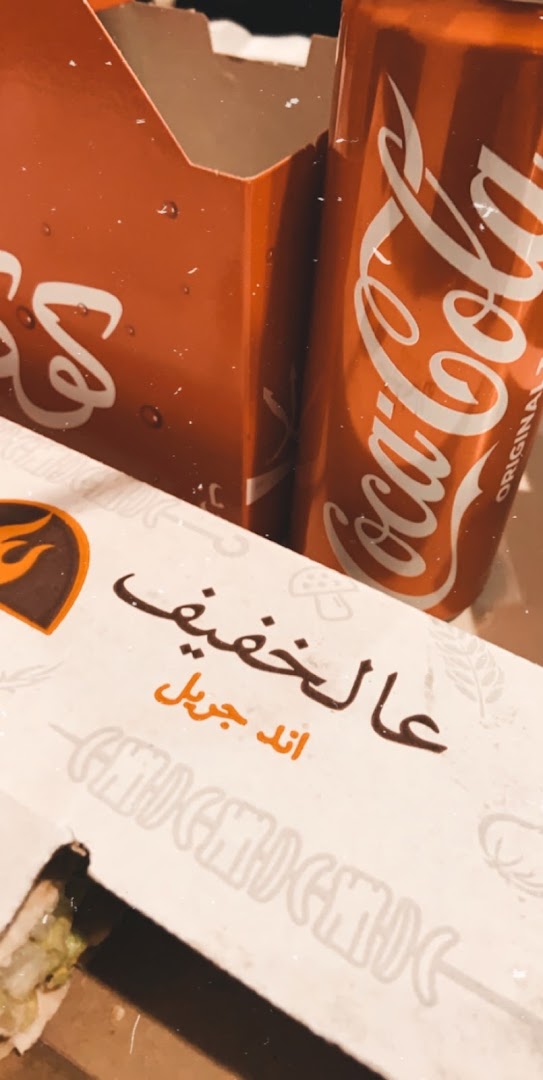 A close-up of a Coca-Cola can and food packaging from Khafif.
