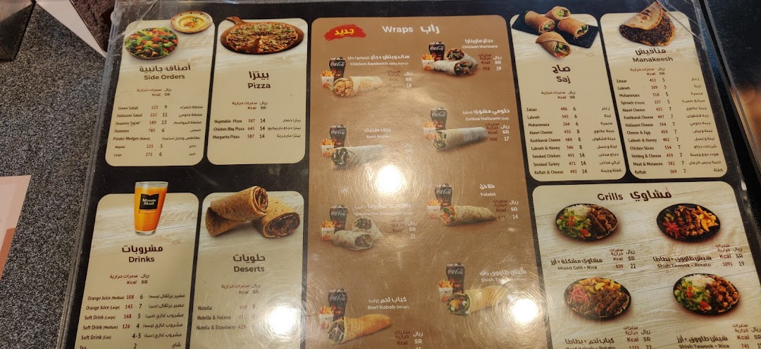 A menu board displaying various food items including pizzas, wraps, saj, manakeesh, grills, desserts, and drinks.
