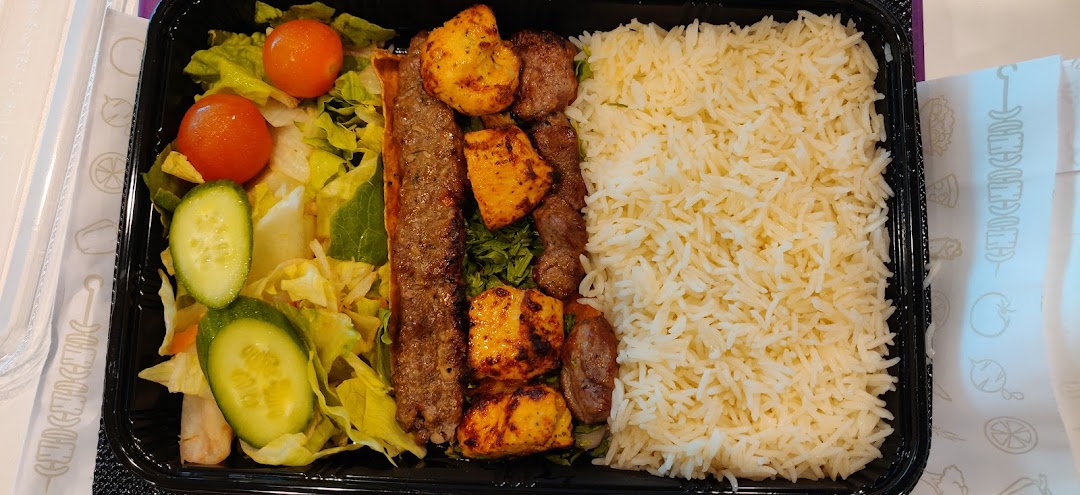 A takeout container filled with rice, salad, and various grilled meats.