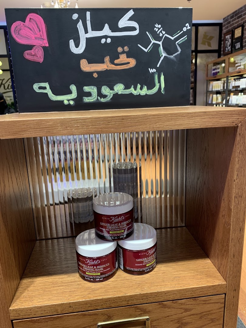 Kiehl's products displayed with Arabic calligraphy and chemical structures on a blackboard.