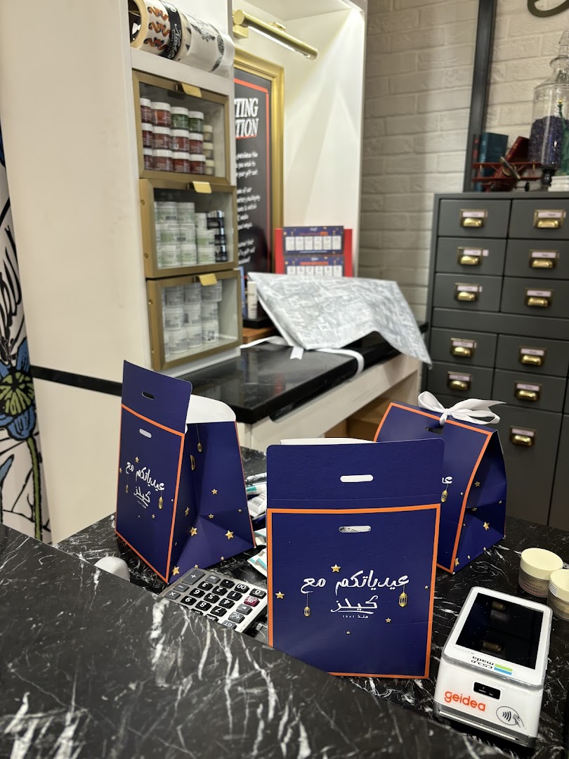 Kiehl's store counter with gift bags, calculator, and payment terminal.