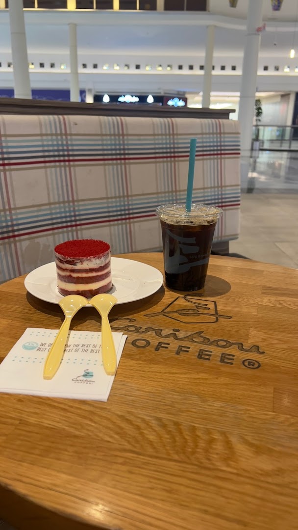 A red velvet cake and an iced coffee on a table at Caribou Coffee.