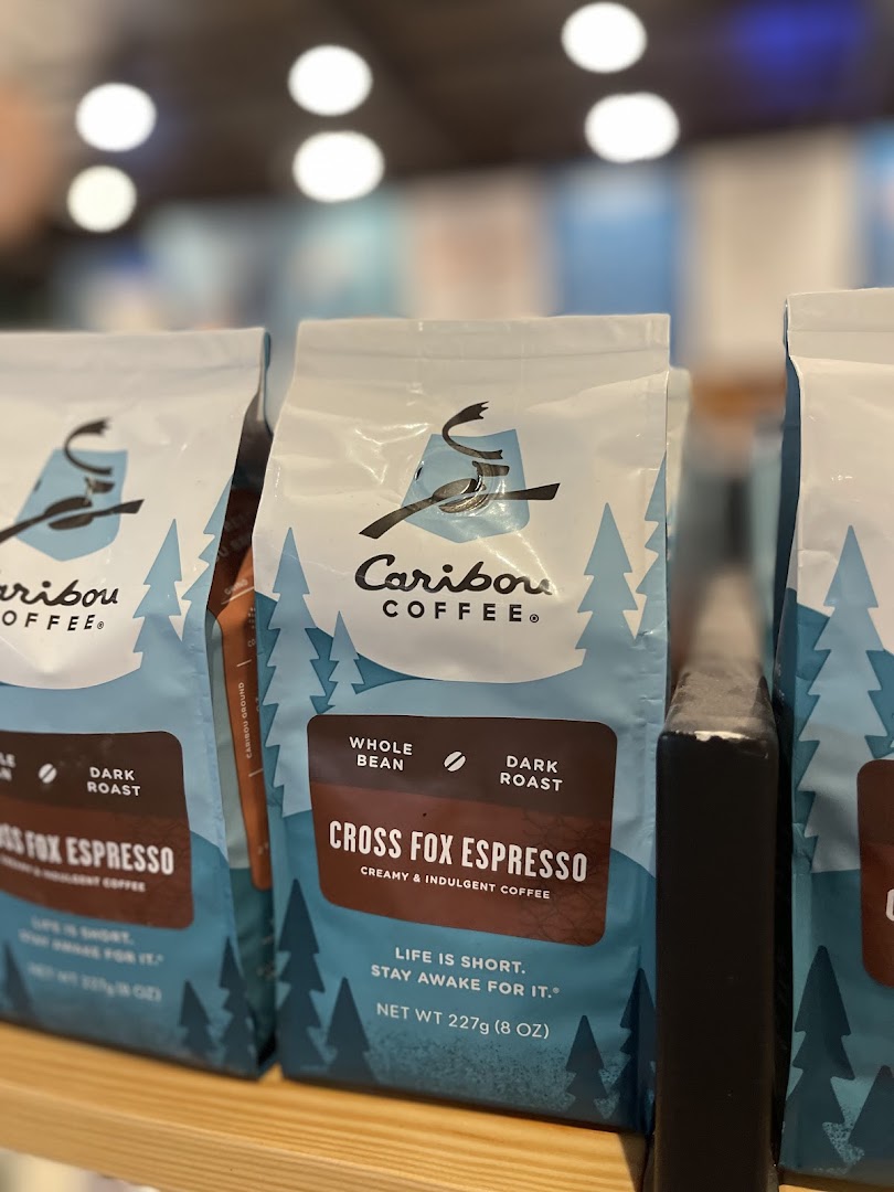 Bags of Caribou Coffee's 'Cross Fox Espresso' dark roast coffee are displayed on a shelf.