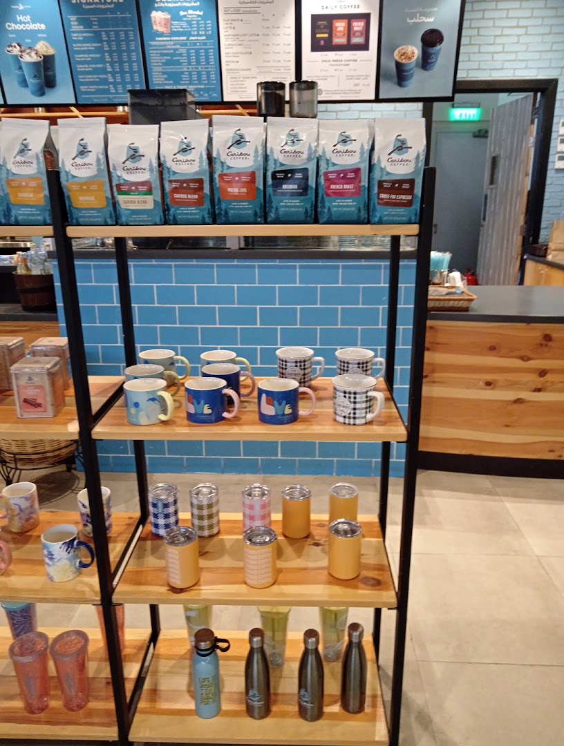 A display of Caribou Coffee products including bags of coffee beans and various mugs and tumblers.