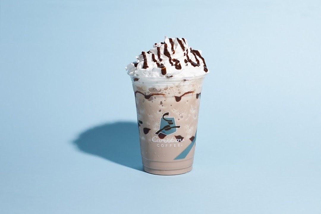 A delicious Caribou Coffee beverage with whipped cream and chocolate drizzle.