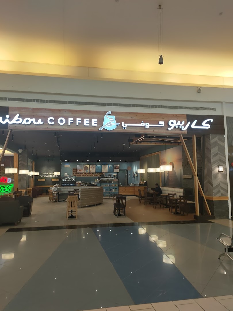 The entrance of Caribou Coffee shop with its logo and seating area visible inside.