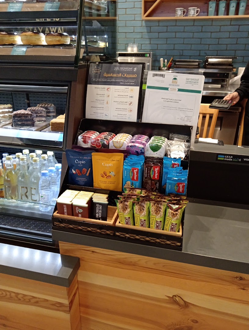 A display of snacks and drinks at Caribou Coffee, with cakes and donuts visible in the background.