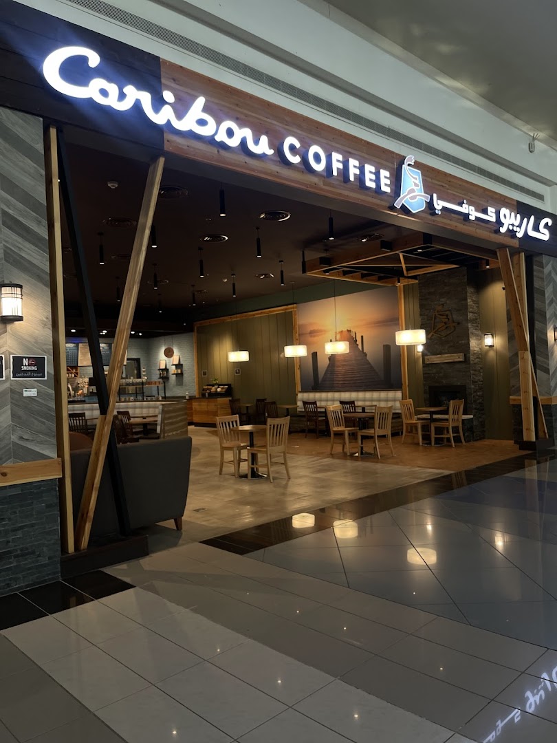 The inviting entrance of Caribou Coffee, showcasing its cozy interior and seating areas.