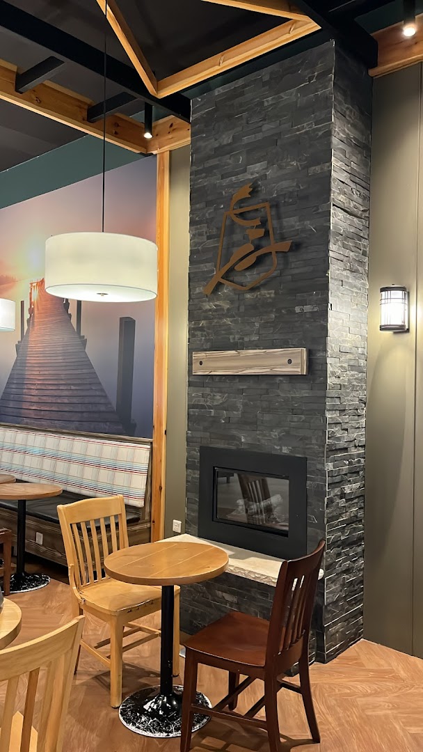 Interior of Caribou Coffee with tables, chairs, and a stone fireplace.