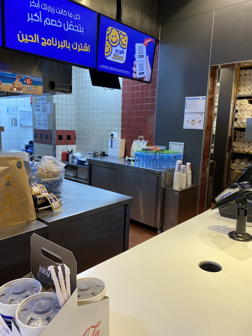 Interior view of a Kudu restaurant counter with drinks and promotional screens.