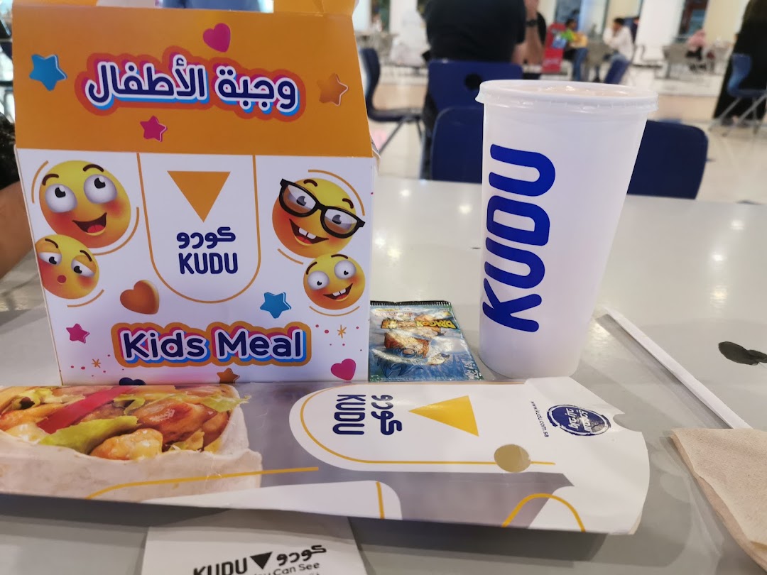 A Kudu kids meal box, drink cup, and food item on a table.