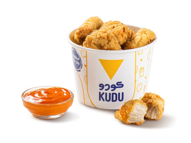 A bucket of crispy fried chicken pieces with a side of dipping sauce.