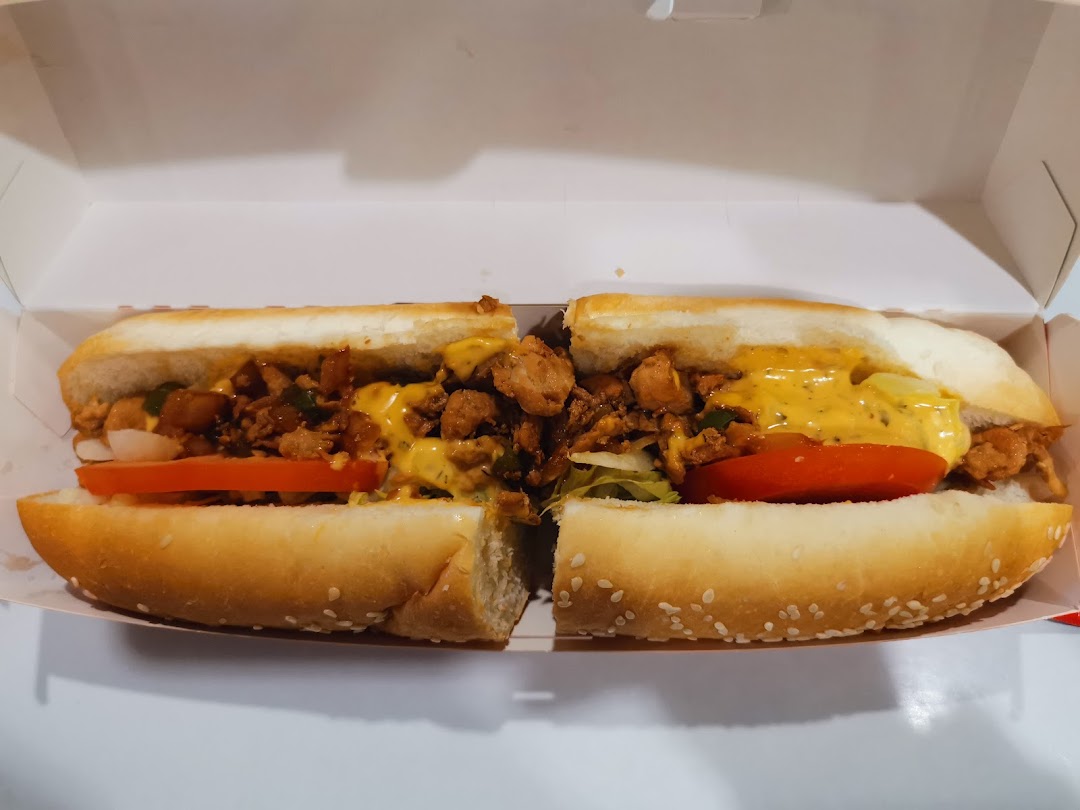 A delicious-looking sandwich with chicken, vegetables, and sauce, cut in half.