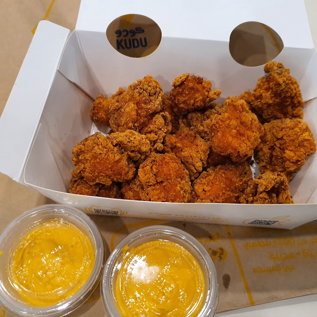 A box of crispy fried chicken bites with two dipping sauces.