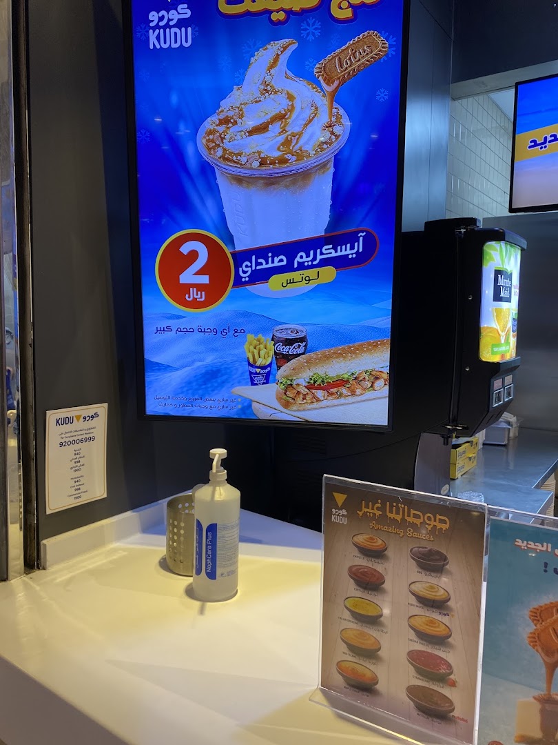 A digital menu board displays a Lotus ice cream sundae and a sandwich combo at Kudu.