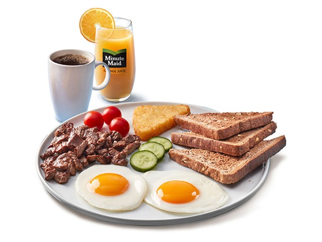 A hearty breakfast plate with steak, eggs, toast, hash brown, and orange juice.