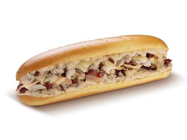 A delicious-looking sandwich with chicken, cheese, and sauce on a bun.