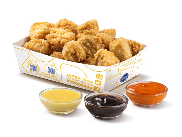 A box of crispy chicken bites served with three dipping sauces.