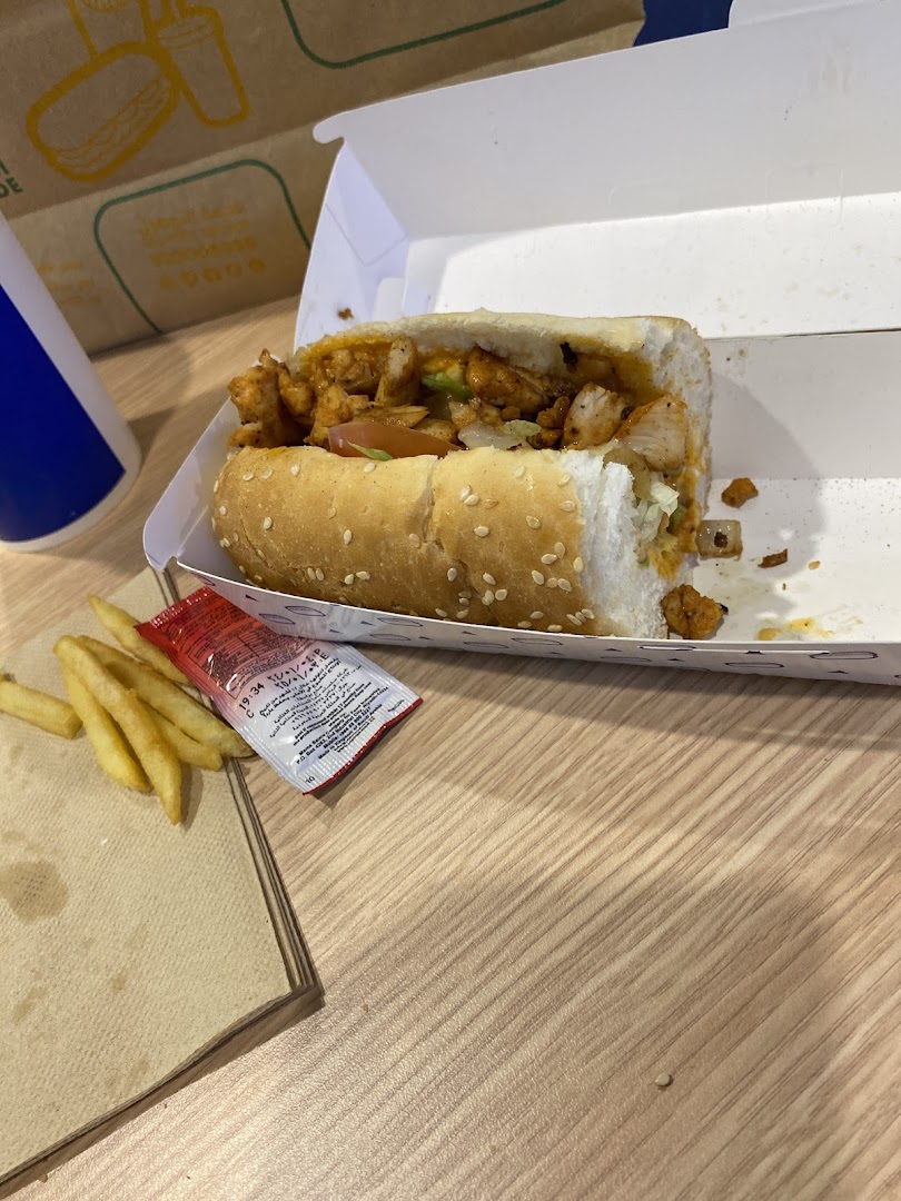 A delicious chicken sandwich with fries and a drink on a wooden table.