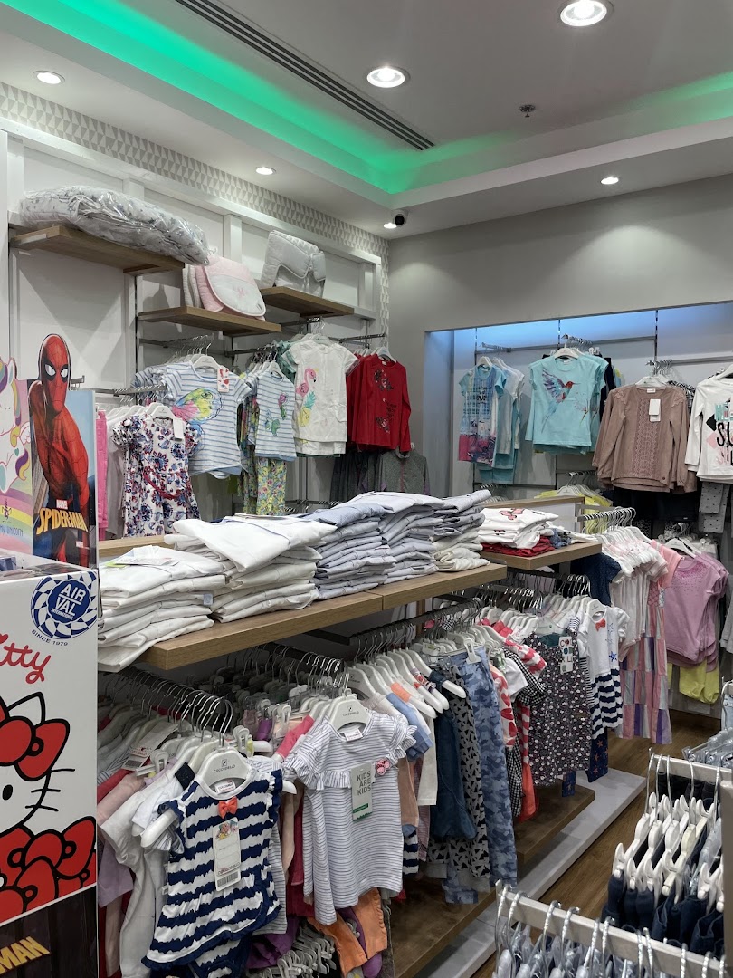 A well-organized retail store interior displaying a wide variety of children's clothing on racks and shelves.