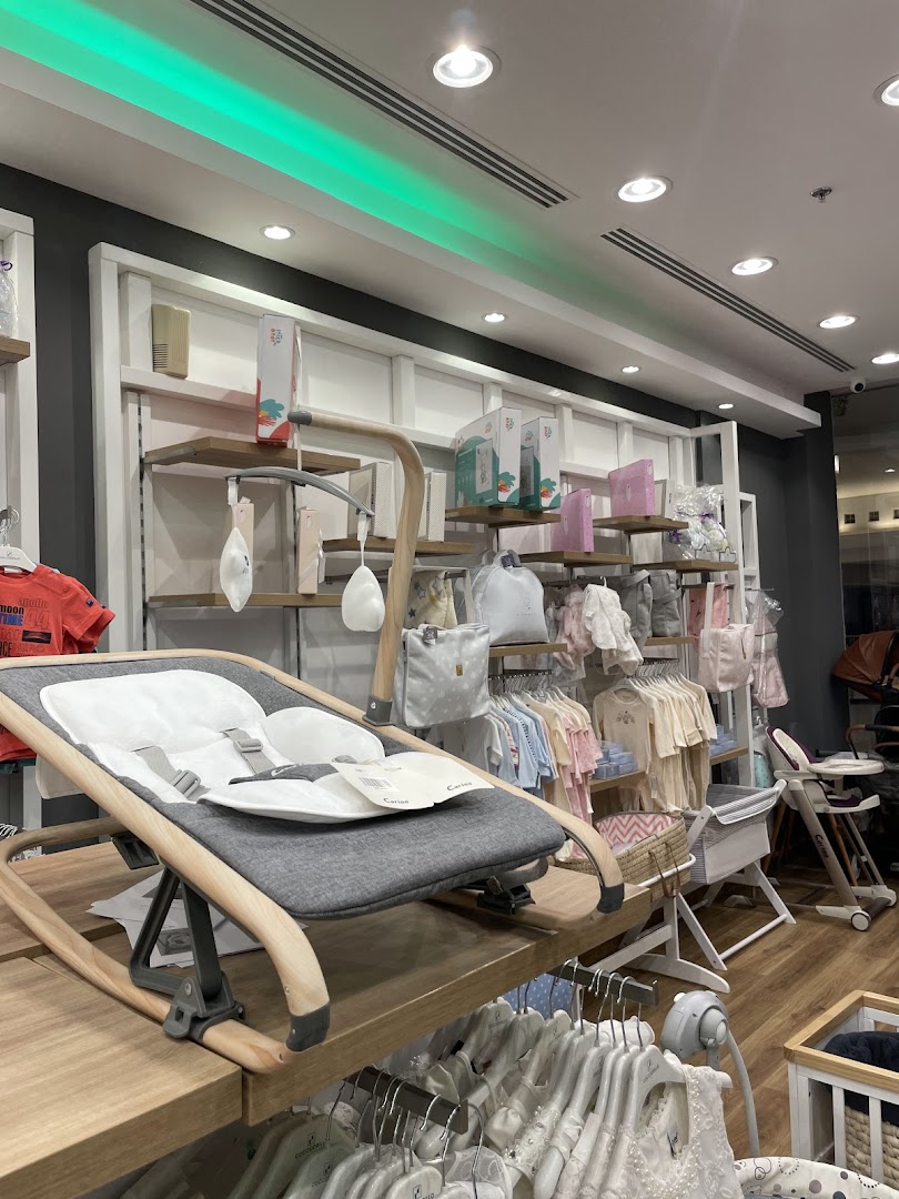 Interior view of a baby clothing and furniture store, showcasing a rocking chair and various apparel.