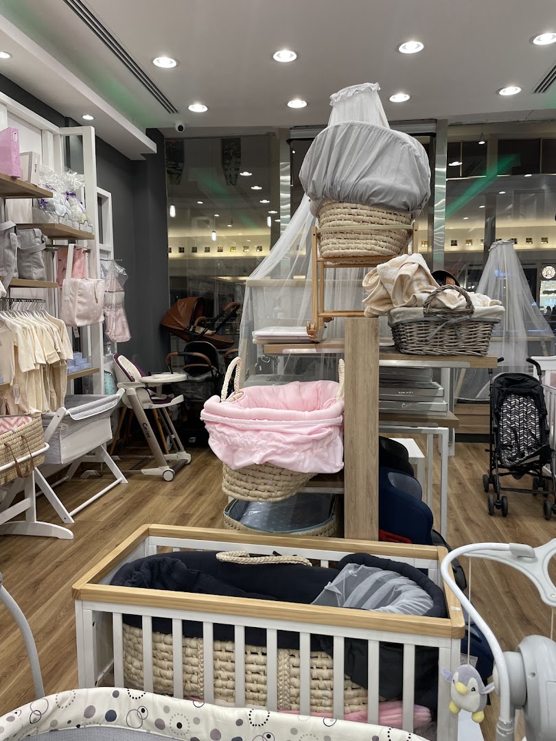 A retail store interior displaying baby cribs, bassinets, strollers, and baby clothing.