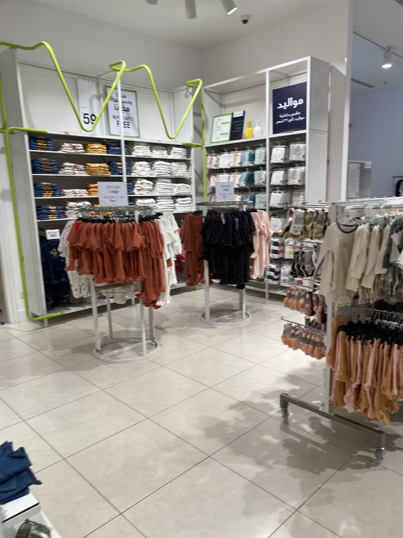 Interior view of a children's clothing store with racks of apparel and sale signs.