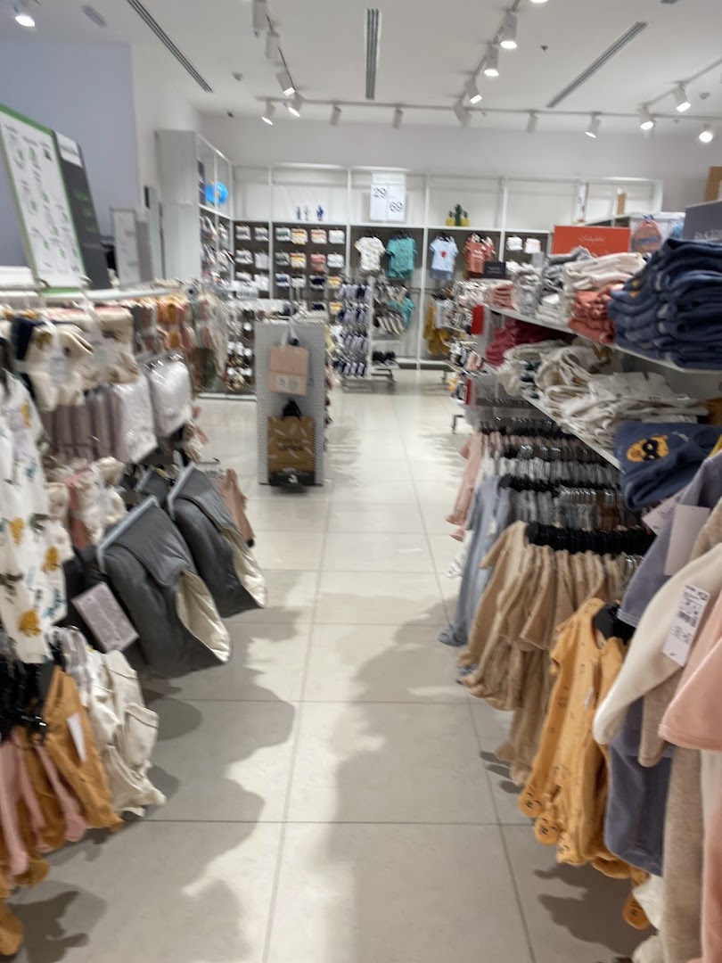 Interior view of a brightly lit children's clothing store with racks of apparel.