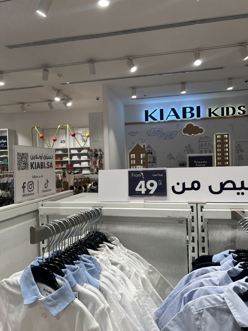 Interior view of a Kiabi Kids store showcasing rows of children's shirts on hangers and a promotional sign.